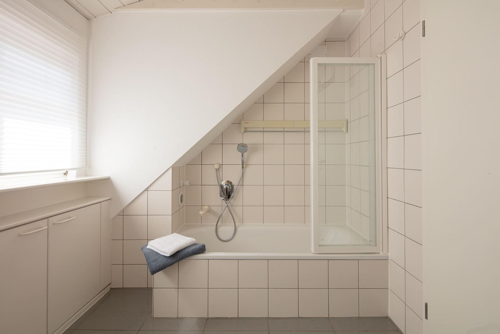 Badezimmer mit Dusche, Badewanne und Fenster