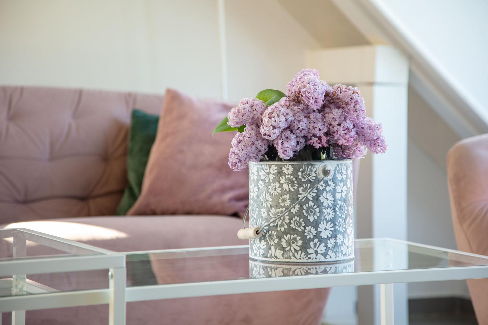 Ein Glas-Tisch mit Blumenkorb und Sofa im Hintergrund.