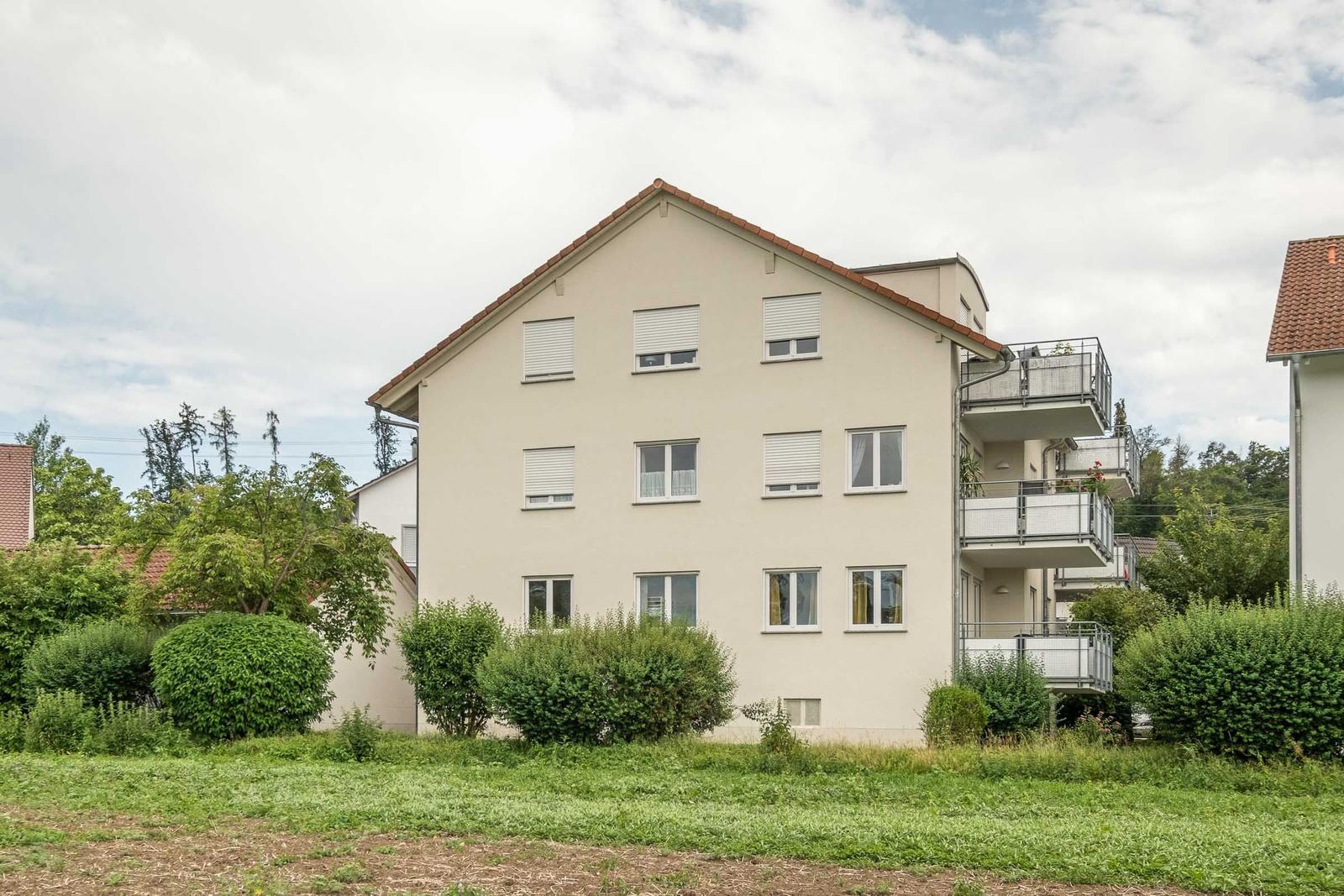 Ein Mehrfamilienhaus mit Balkonen und grüner Umgebung.