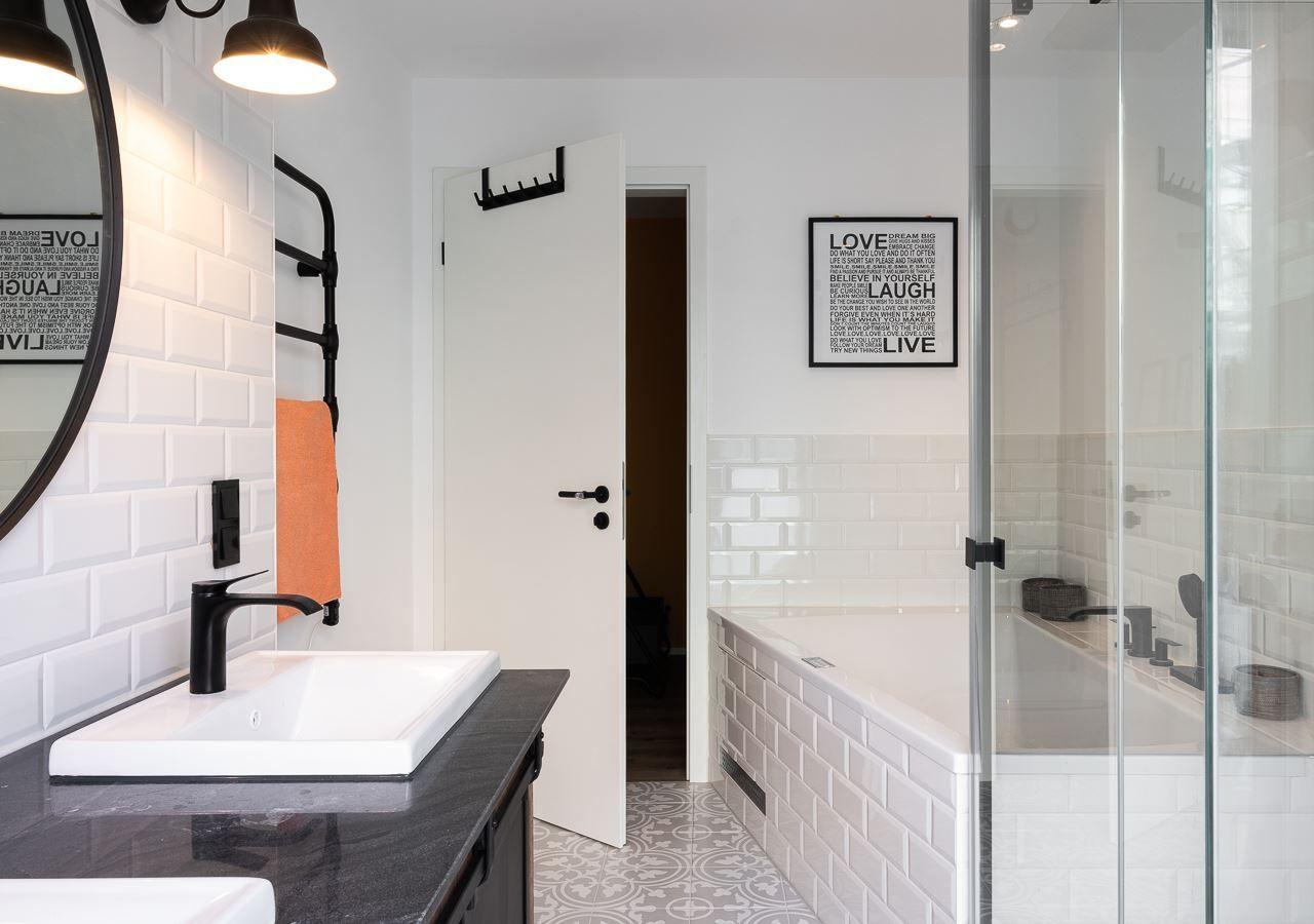 Badezimmer mit Dusche, Waschbecken und Wandfliesen