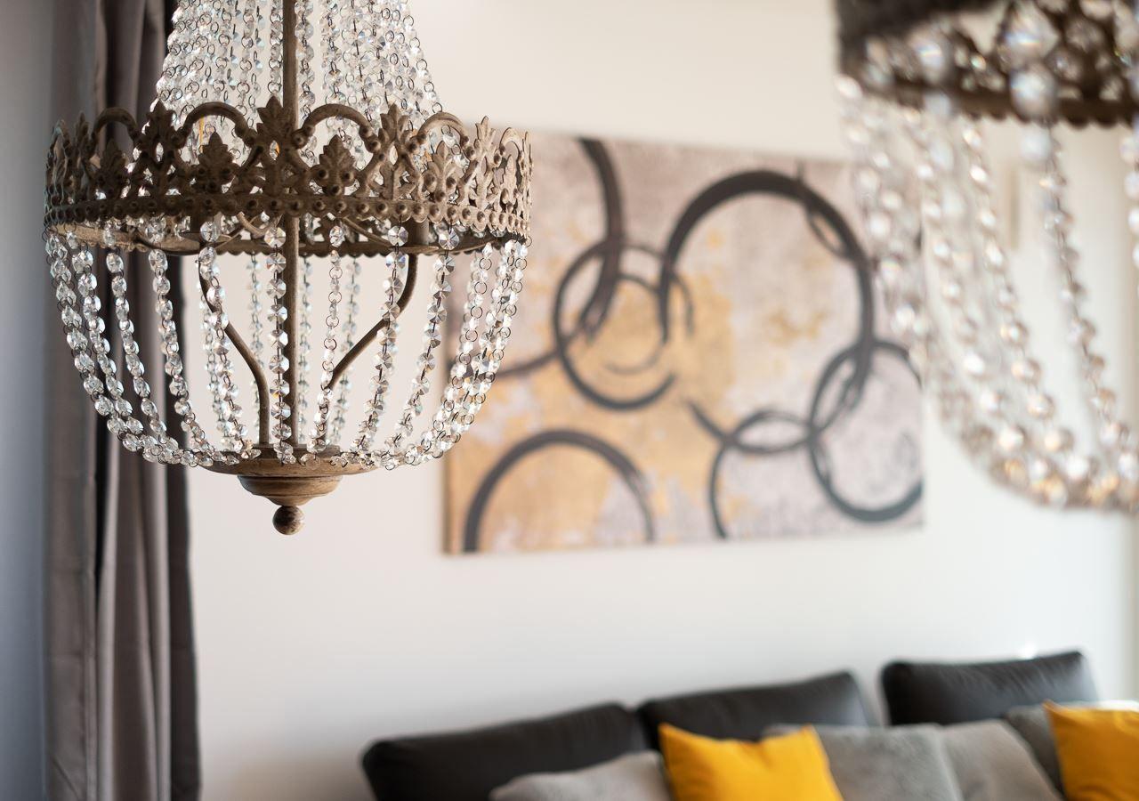 Ein Raum mit einer Kronleuchter und einem Wandbild über einem Sofa.