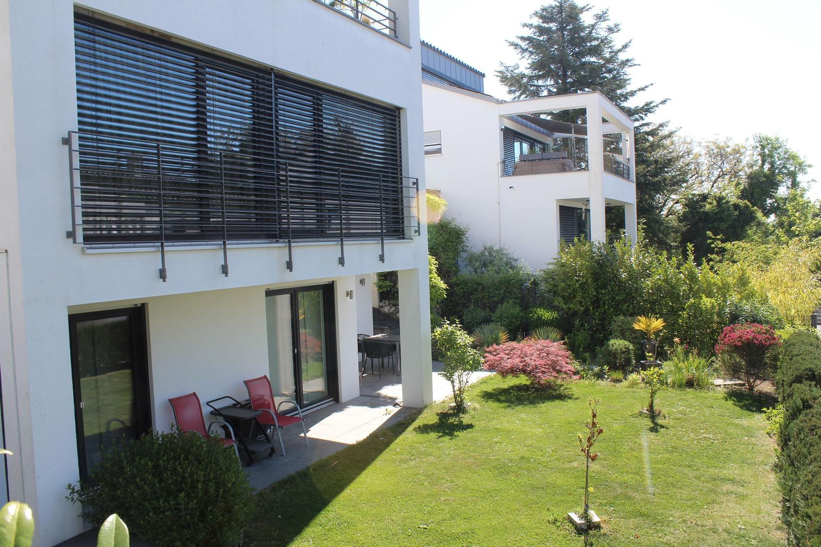 Moderne Villa mit Balkon, Garten und Sitzgelegenheiten.