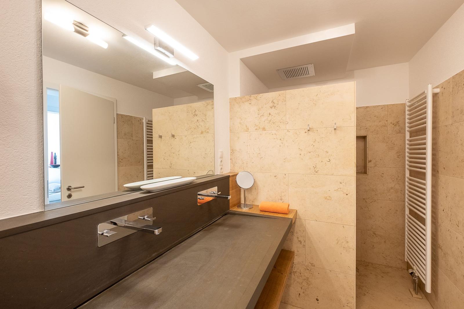 Badezimmer mit Dusche, Waschbecken und Spiegel