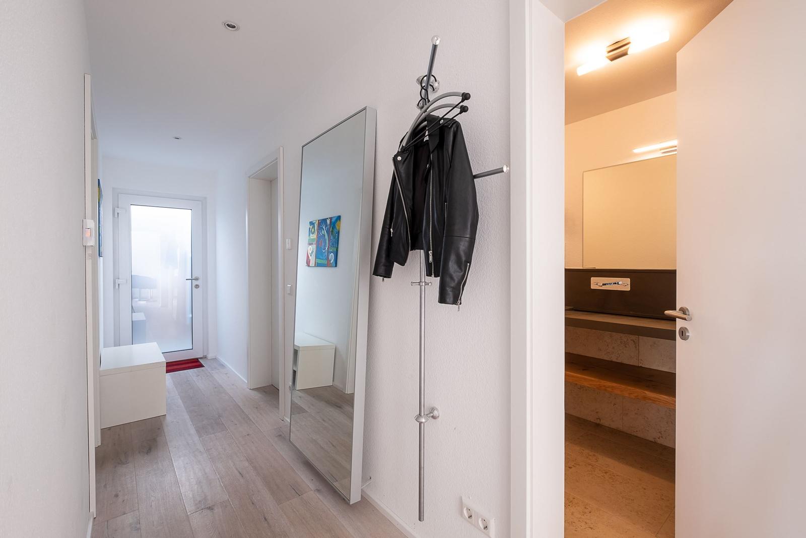 Flur mit Spiegel, Jacke und Blick in Bad