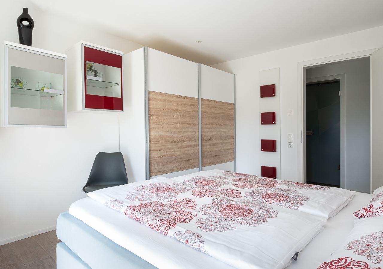 Schlafzimmer mit Bett, Kleiderschrank und Wandregalen.