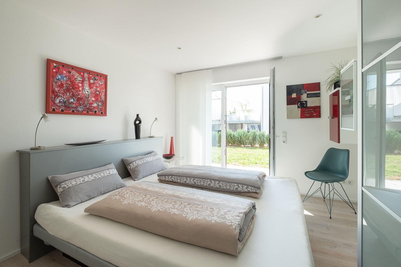 Schlafzimmer mit Bett, Kunst an den Wänden und Blick auf einen Garten.