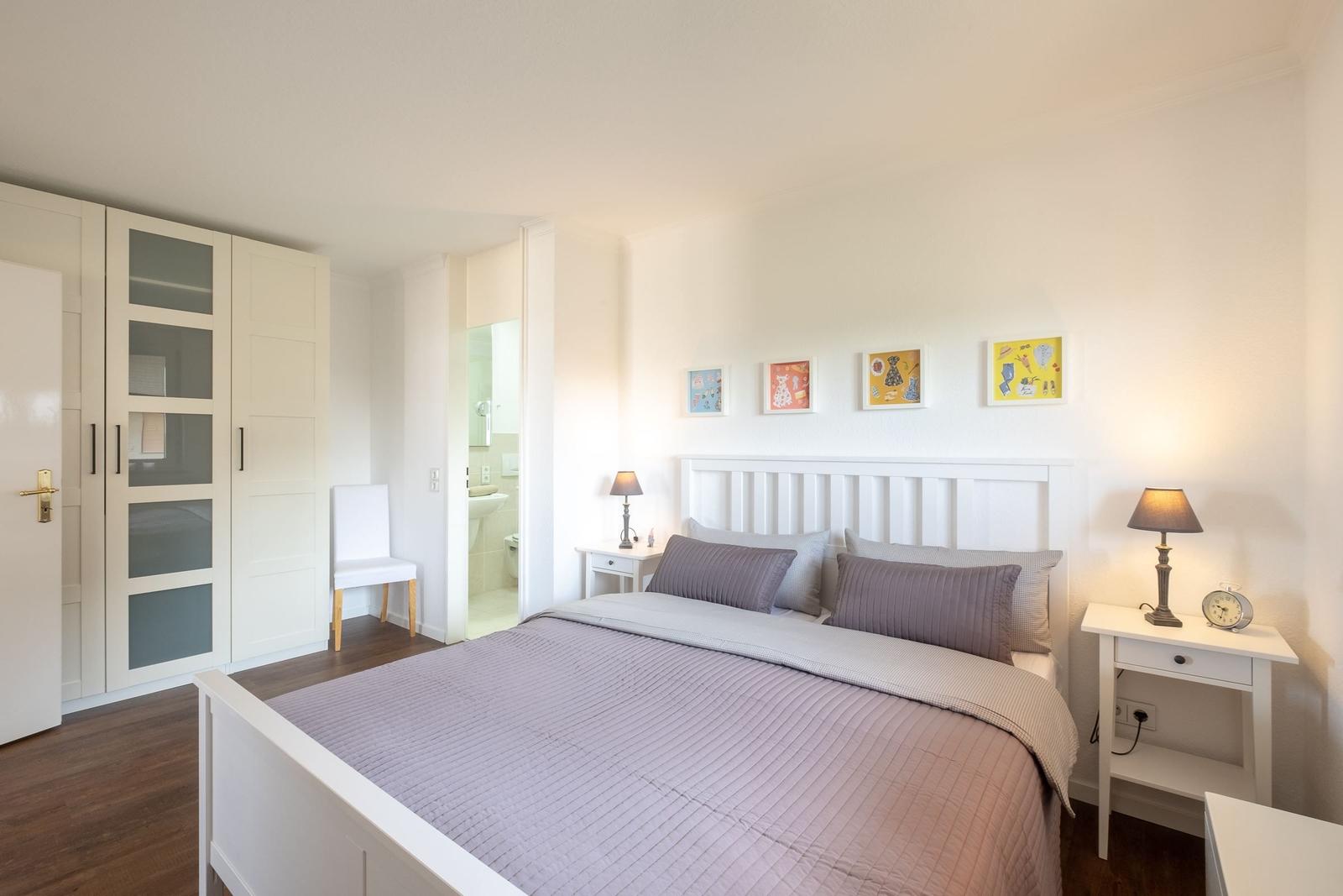 Schlafzimmer mit Bett, Nachttischen und Kleiderschrank. Badezimmer ist angebunden.