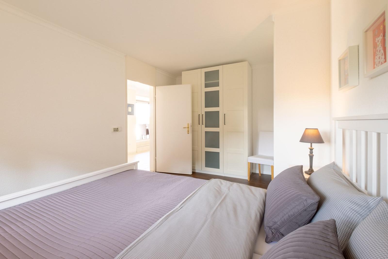 Schlafzimmer mit Bett, Kleiderschrank und Nachttischlampe.
