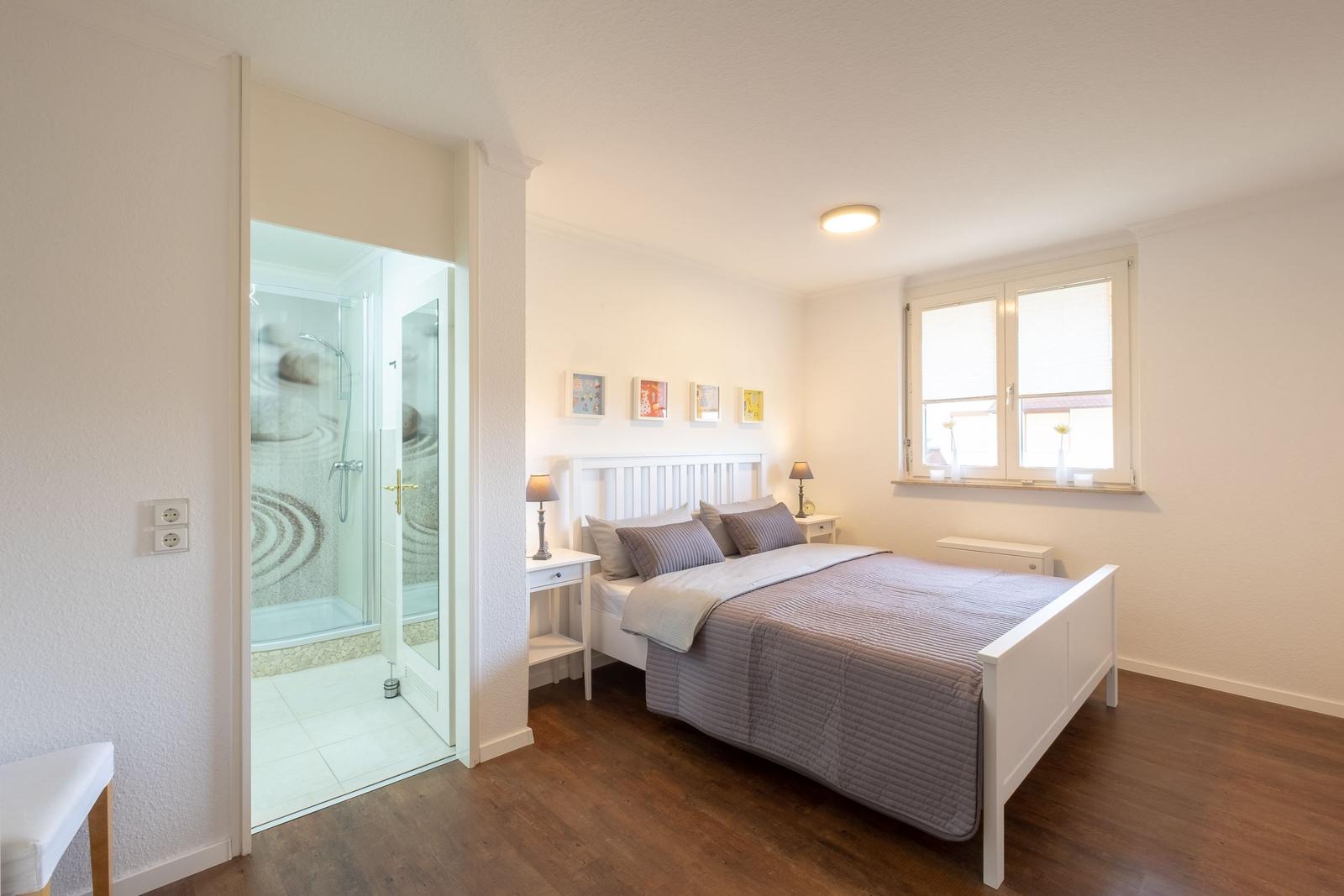 Schlafzimmer mit Doppelbett und angrenzender Dusche.