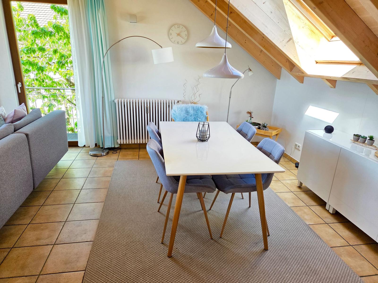 Essbereich mit Tisch, Stühlen und Sitzgelegenheit. Dachgeschoss mit Holzkonstruktion und Fenster.