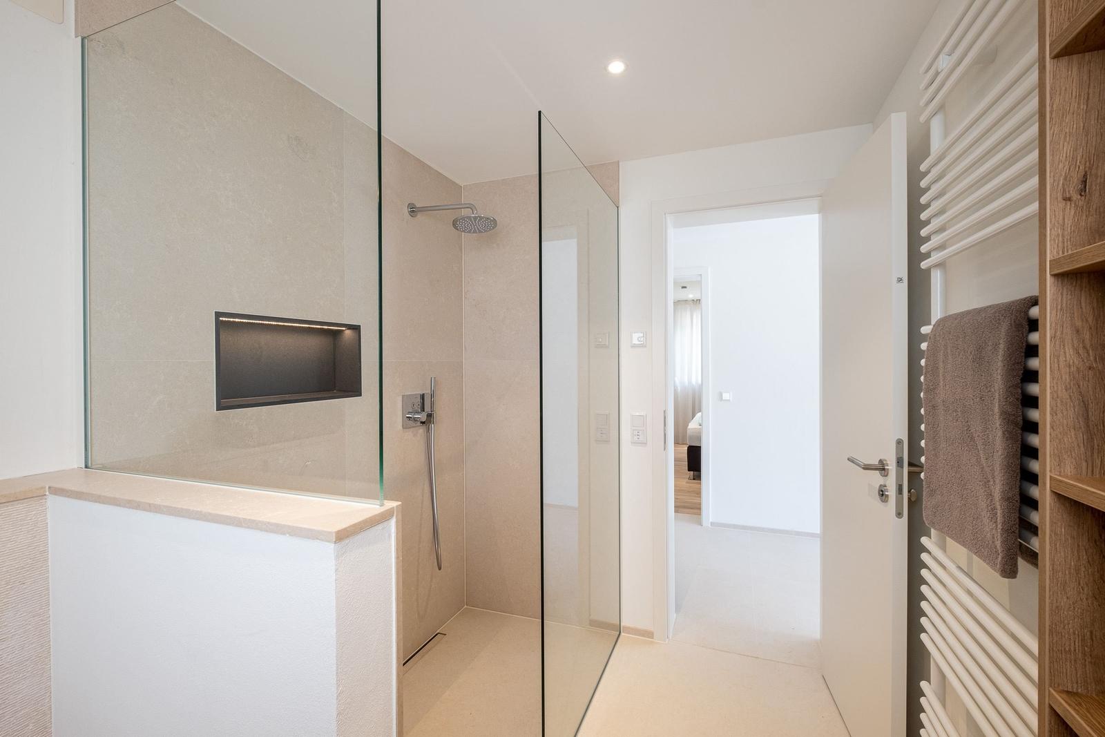 Dusche mit Glaswand, Handtuchhalter und Blick in Schlafzimmer