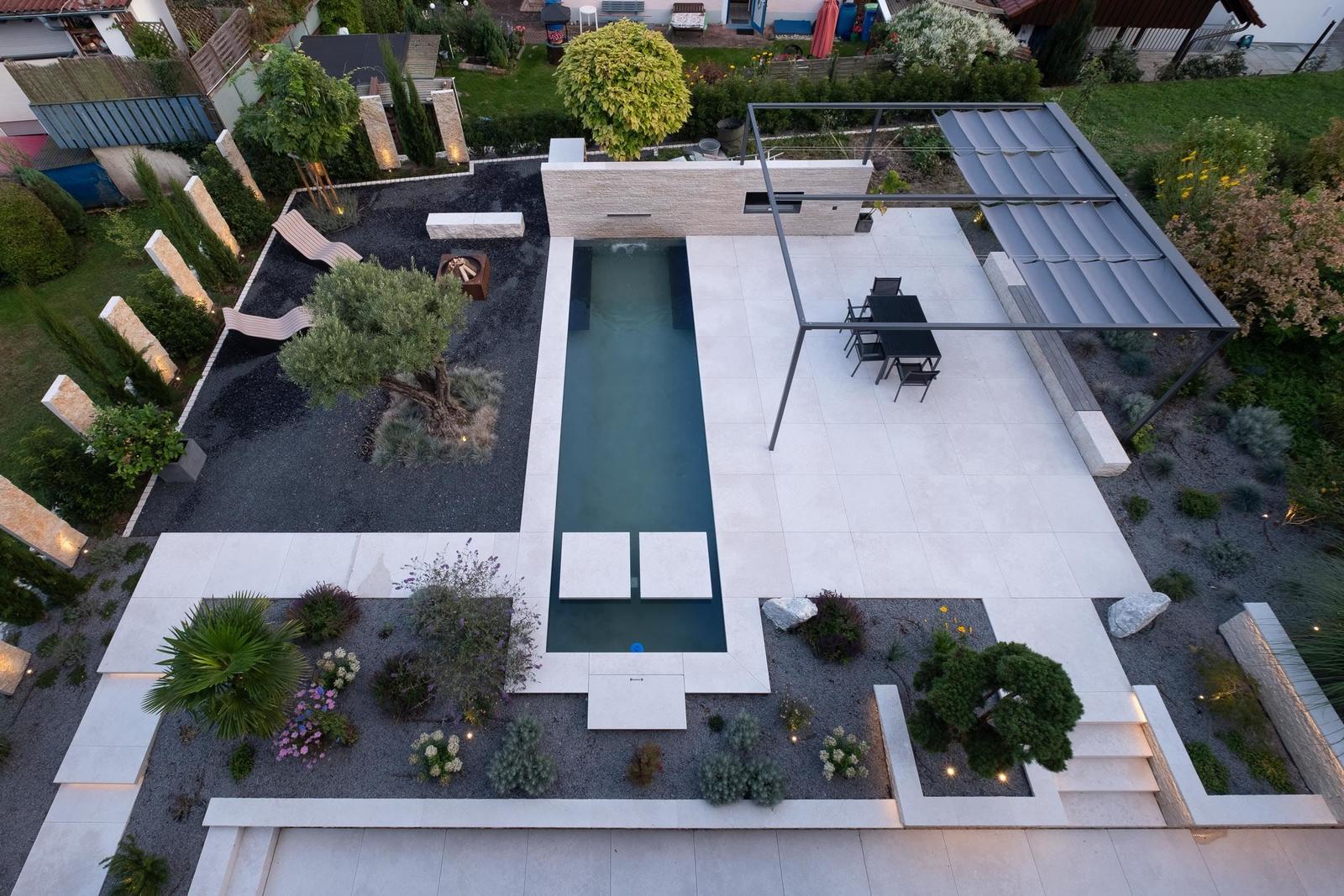 Poolbereich mit Loungebereich und modernem Pavillon im Garten.