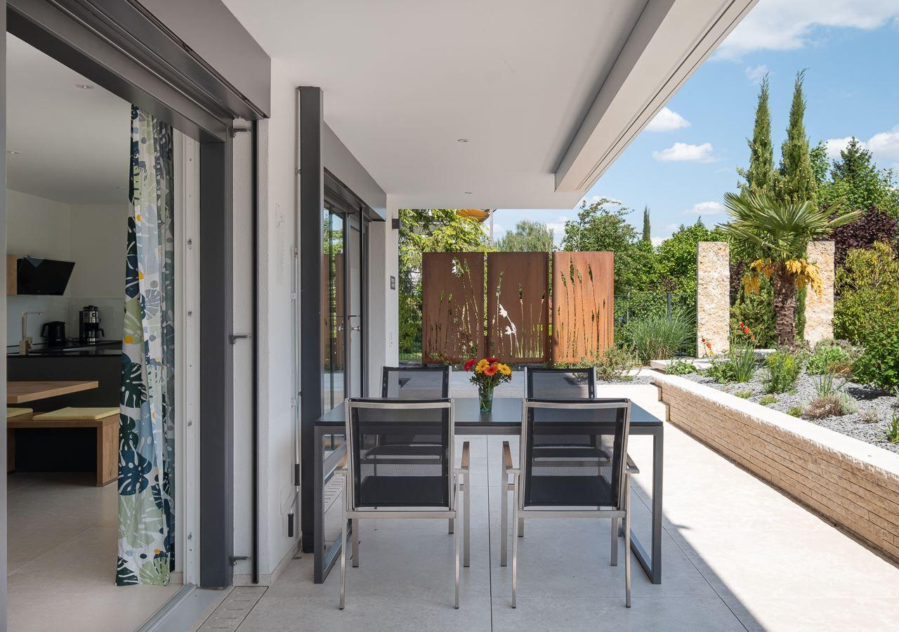 Terrasse mit Esstisch, Garten und Blick ins Haus.