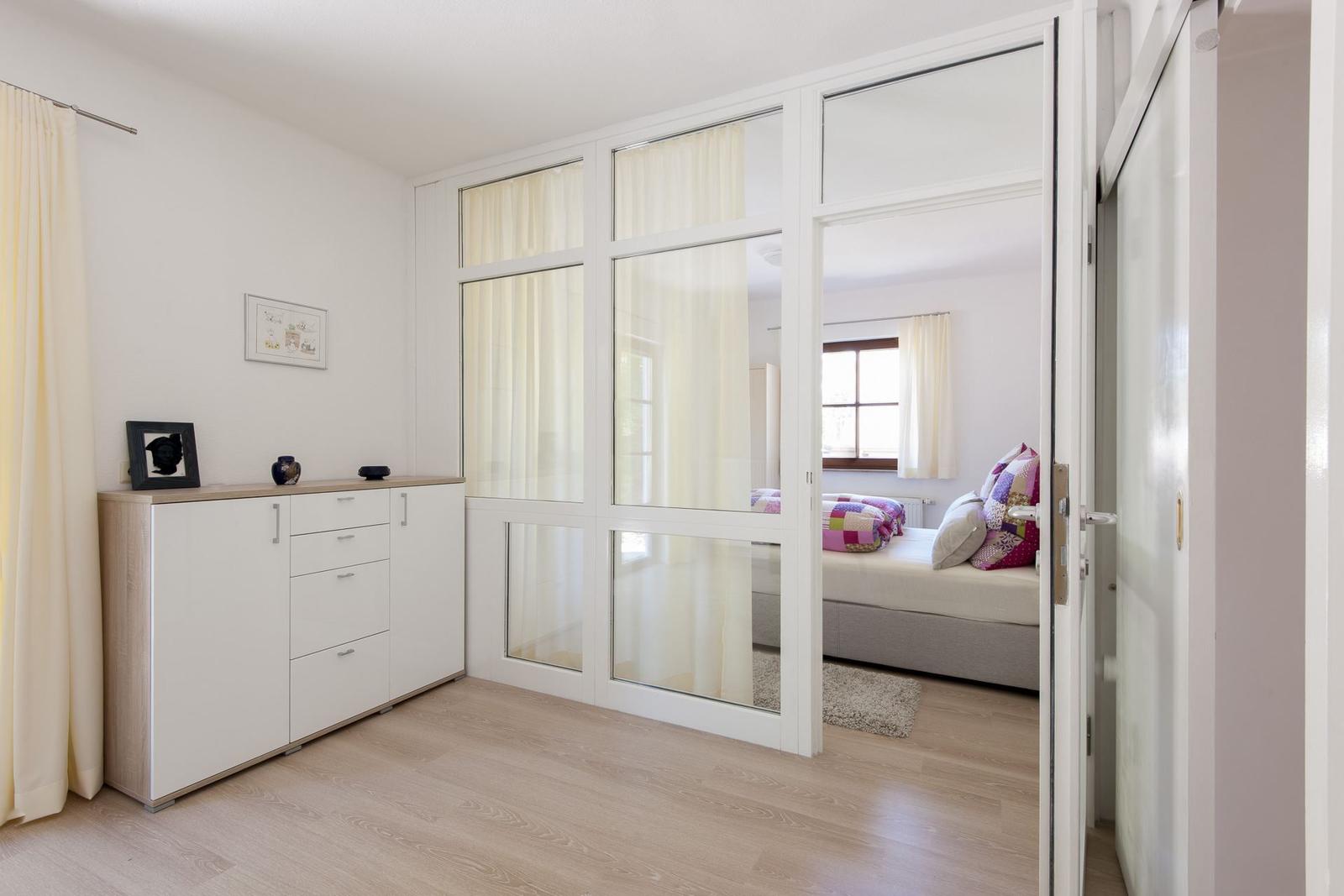 Schlafzimmer mit Schlafbereich und Schrank. Lichtdurchfluteter Raum mit Holzboden.