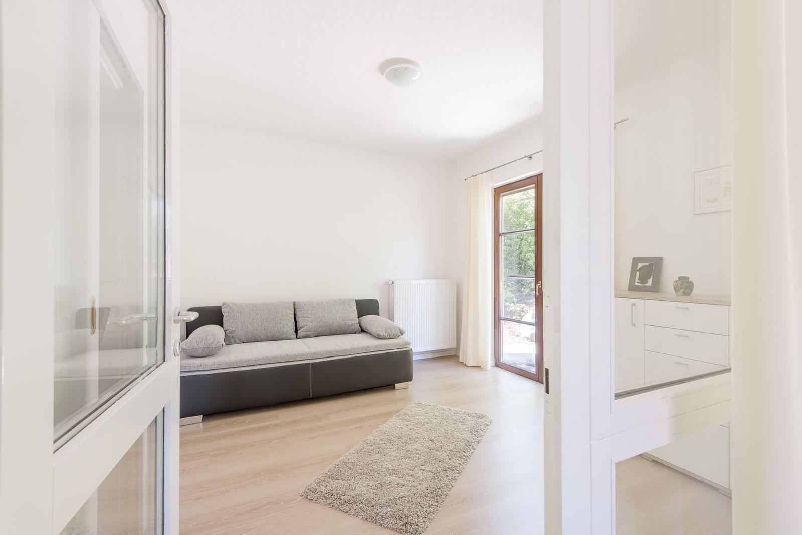Ein Raum mit Sofa, Holzboden und Tür zum Garten.