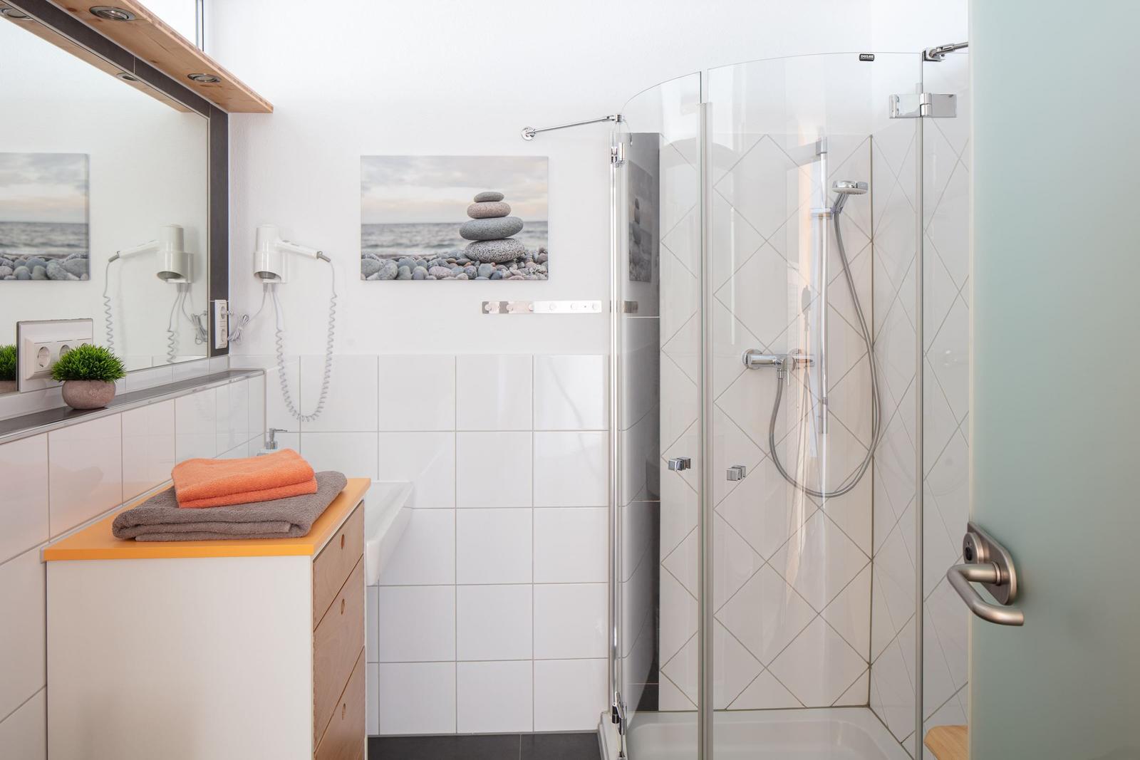 Bad mit Dusche, Waschbecken und Spiegel. Wandbild mit Steinen.