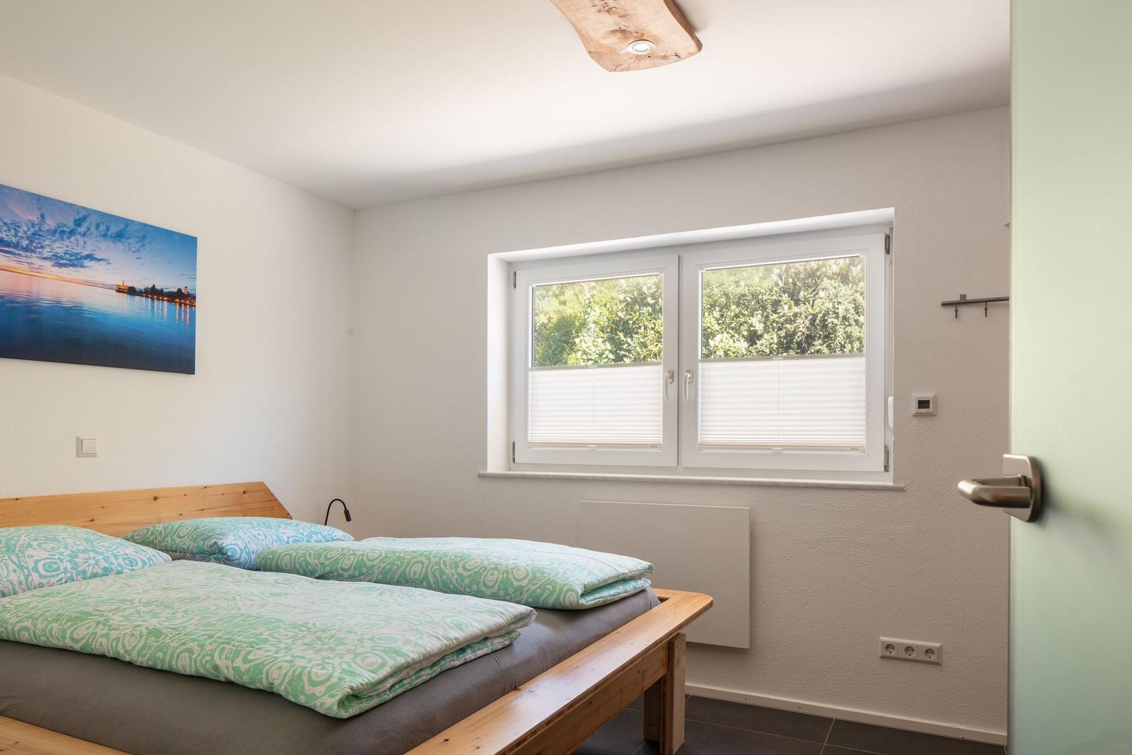 Schlafzimmer mit Doppelbett, Fenster und Wandbild