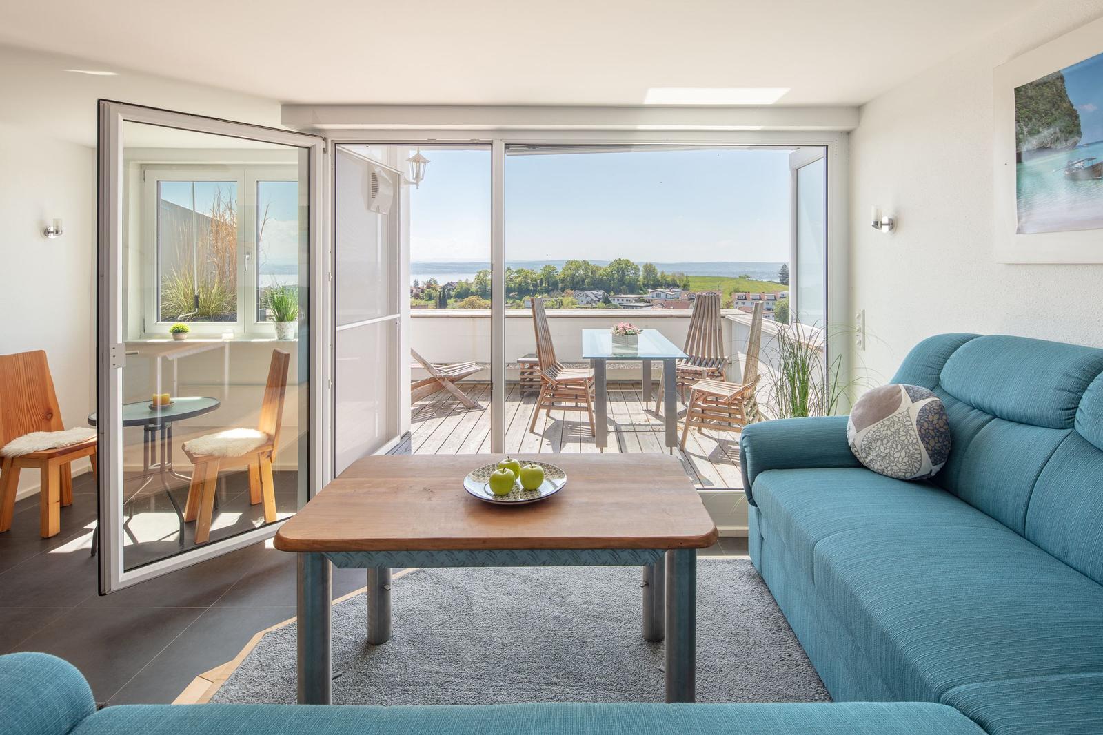 Wohnzimmer mit blauem Sofa und Balkonblick auf See