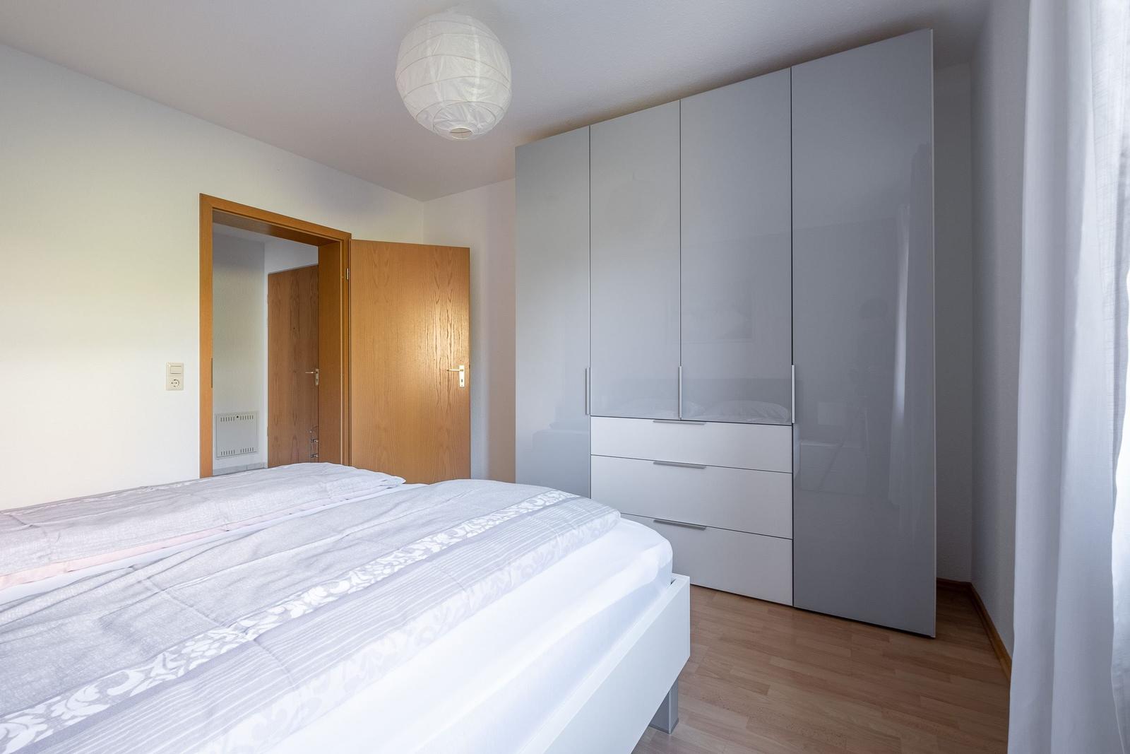 Schlafzimmer mit Bett, Kleiderschrank und Holzboden.