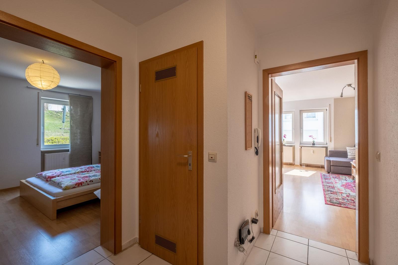 Hausgang mit Schlafzimmer und Wohnzimmer. Holztüren und helle Wände.