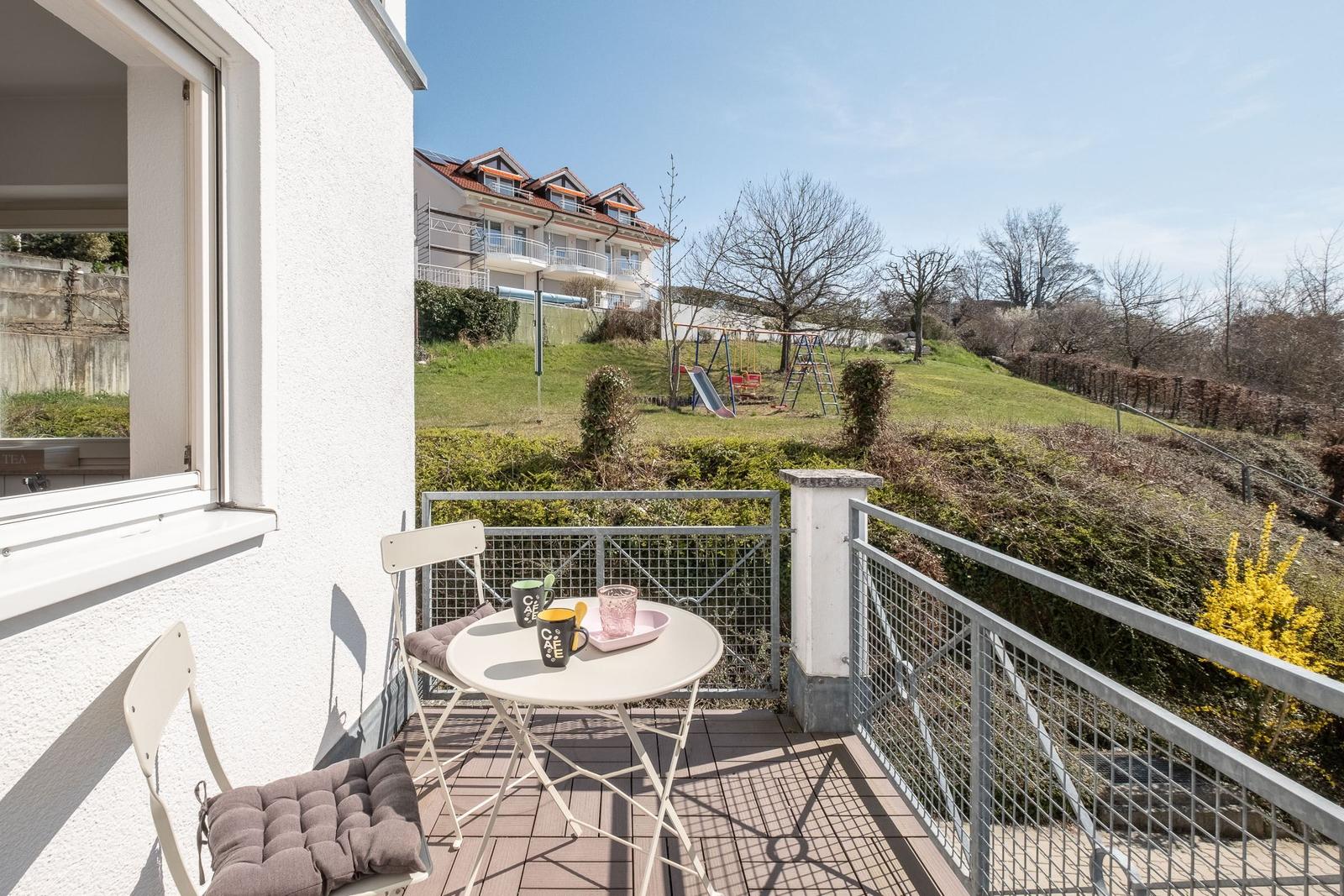 Terrasse mit Tisch und Stühlen. Blick auf Garten und Spielplatz.