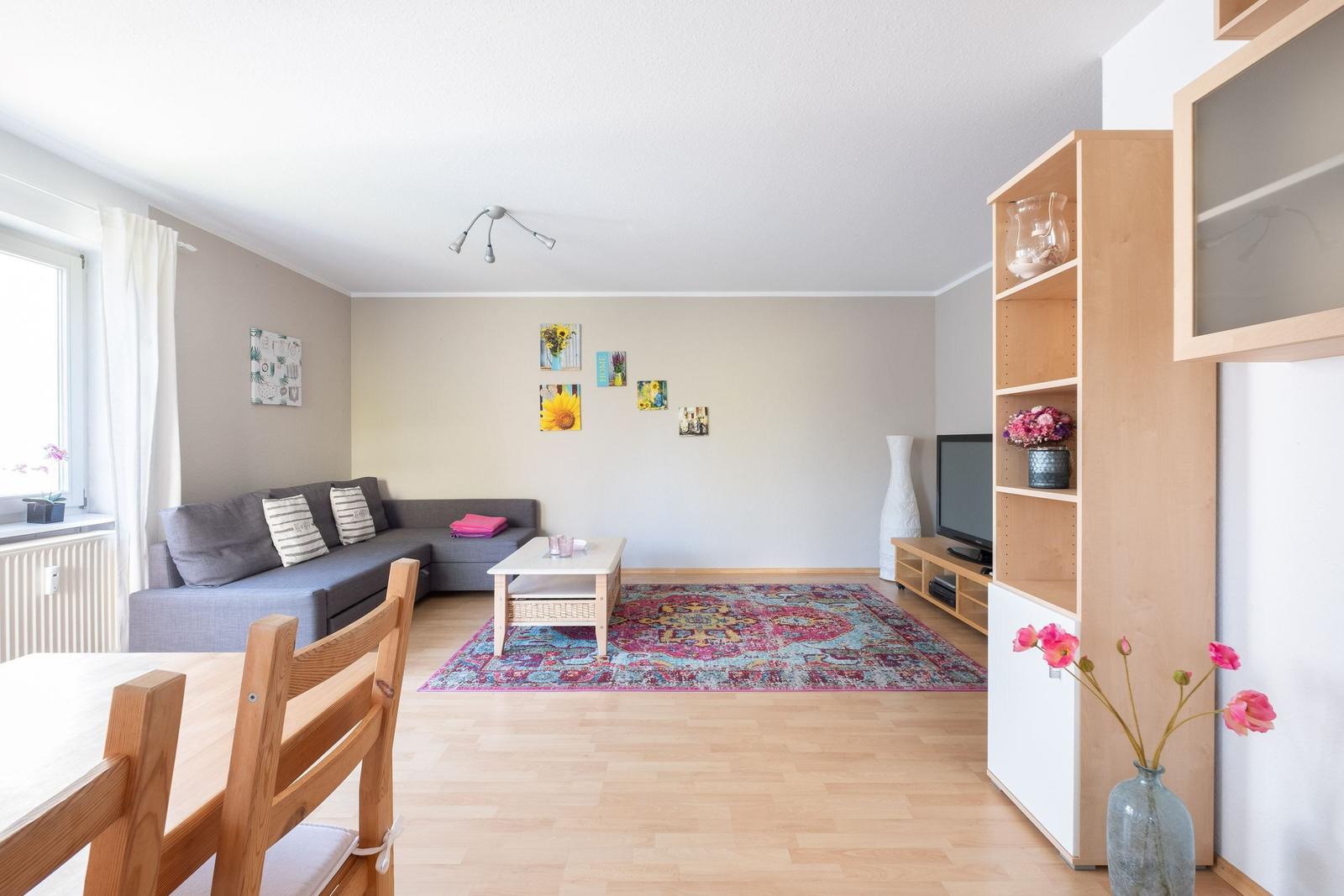 Wohnzimmer mit Sofa, Tisch, Teppich und TV-Möbel. Holzboden und Wanddekoration.