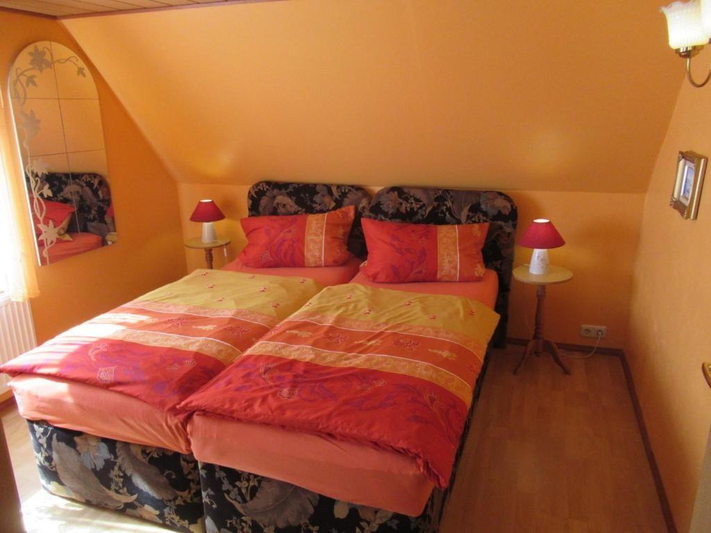 Zwei Einzelbetten mit bunten Bettwäsche, zwei Nachttische mit Lampen und ein Spiegel an der Wand.