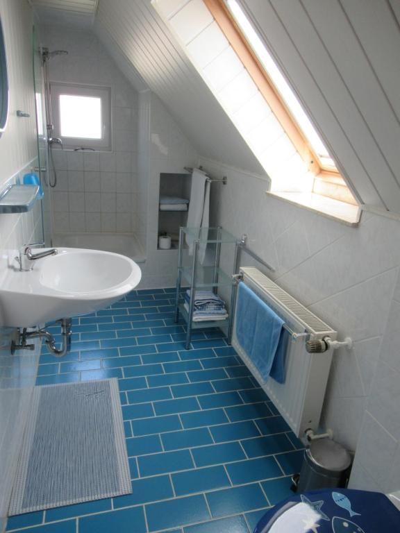 Badezimmer mit Dusche, Waschbecken und blauen Fliesen unter Dachschrägen