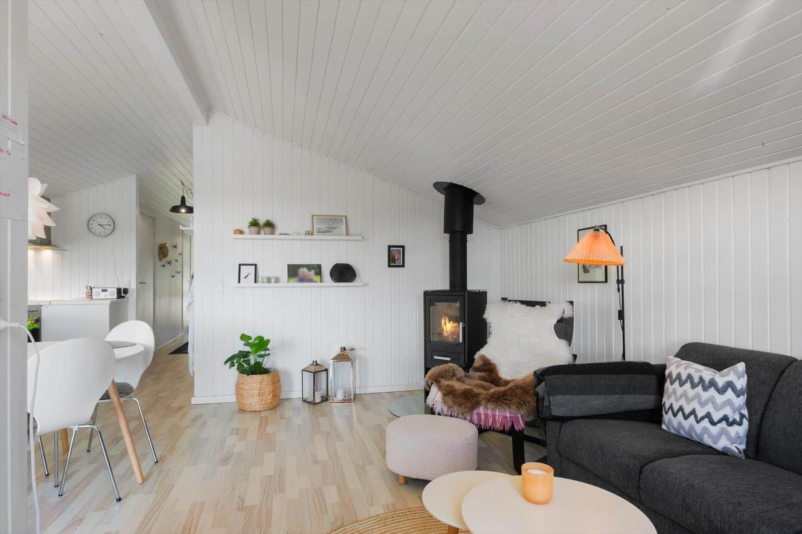 Wohnraum mit Sofa, Kamin und Holzboden. Weiße Wände und Decke.