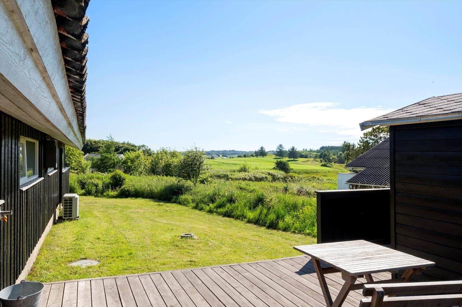 Terrasse mit Tisch und Blick auf grünes Feld und Himmel