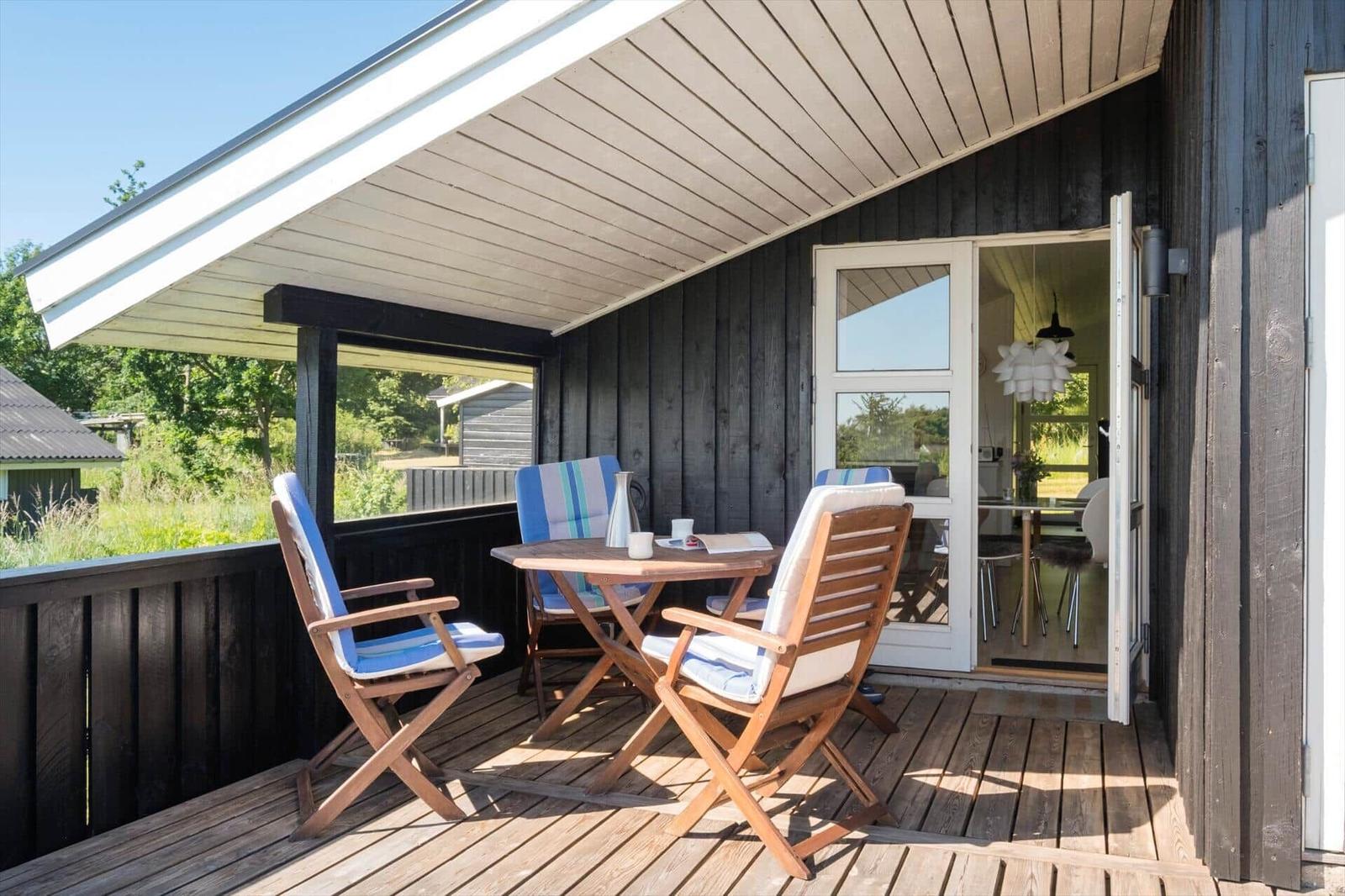Terrasse mit Tisch und Stühlen, Blick in das Haus mit Essbereich.