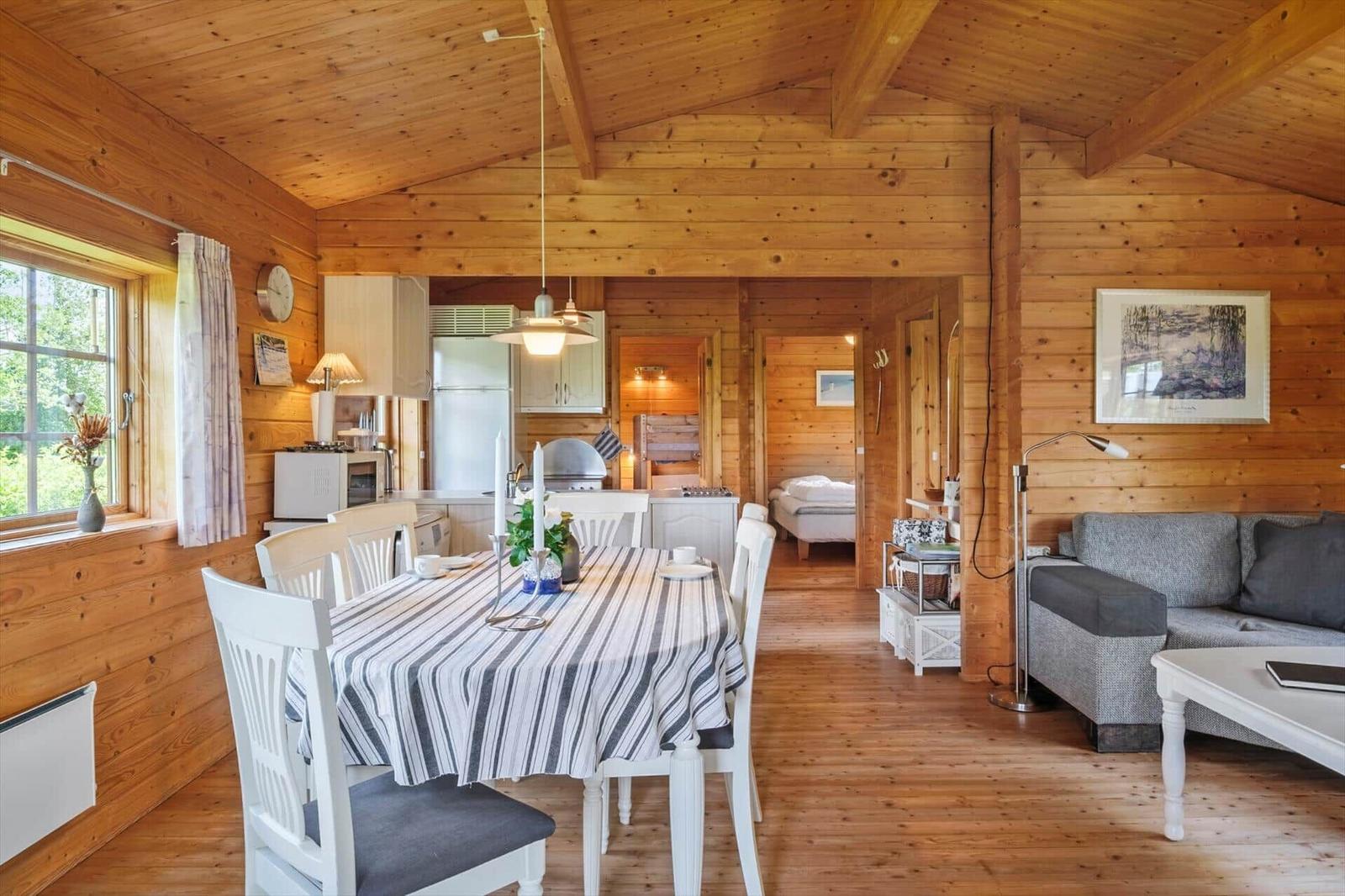 Ein Esszimmer mit Tisch und Stühlen, Küche und Wohnbereich in einem Holzhaus.