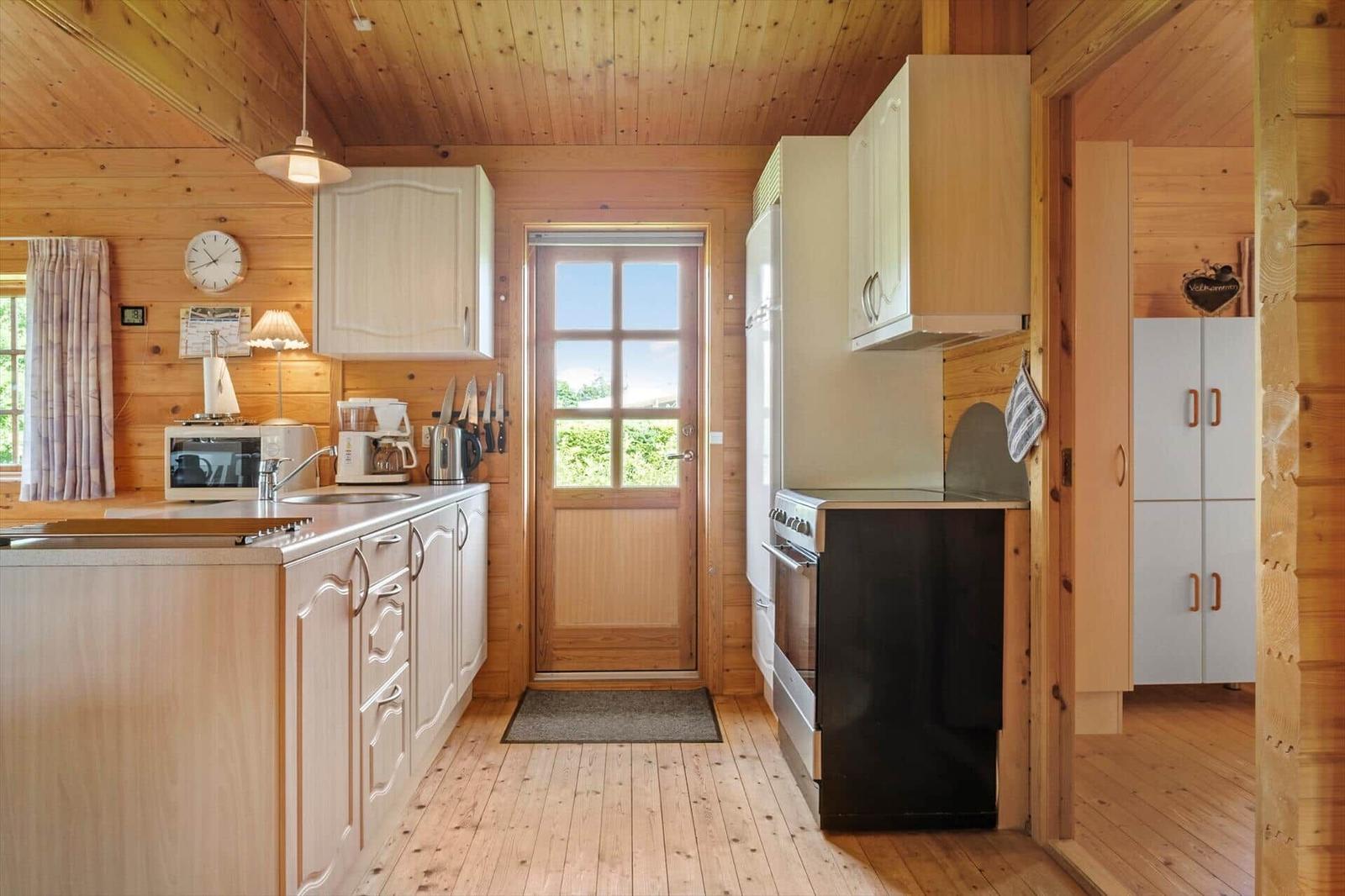 Küche mit Holzwand, Küchenzeile und Tür zum Garten.