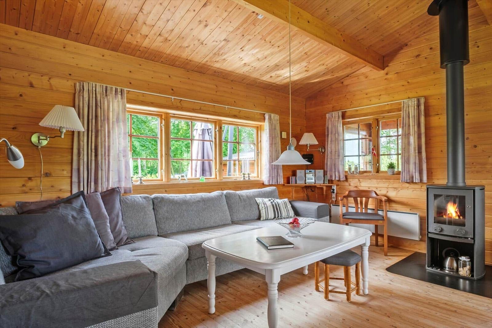 Wohnzimmer mit Holzwand, Sofa, Tisch und Kaminofen.