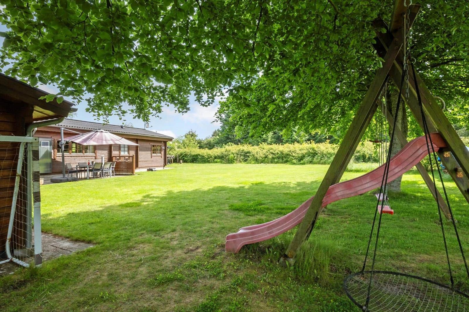 Hinterhof mit Spielplatz, Rutsche und Sitzgelegenheit unter Bäumen.