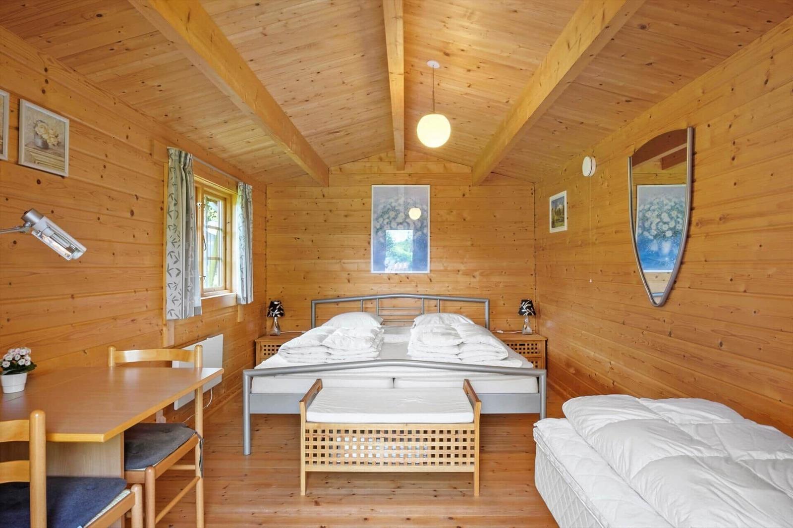 Schlafzimmer mit Holzwand, Bett, Schreibtisch und Fenster.
