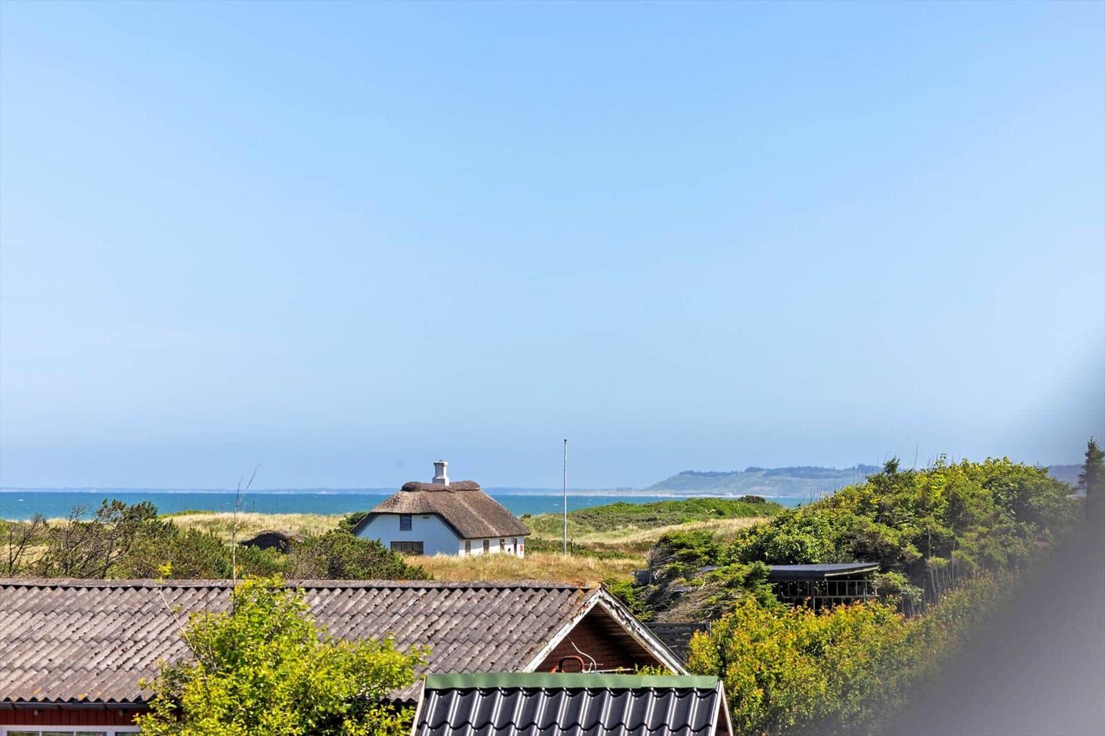 Weitläufige Aussicht auf das Meer und eine weiße Hütte mit strohgedecktem Dach.
