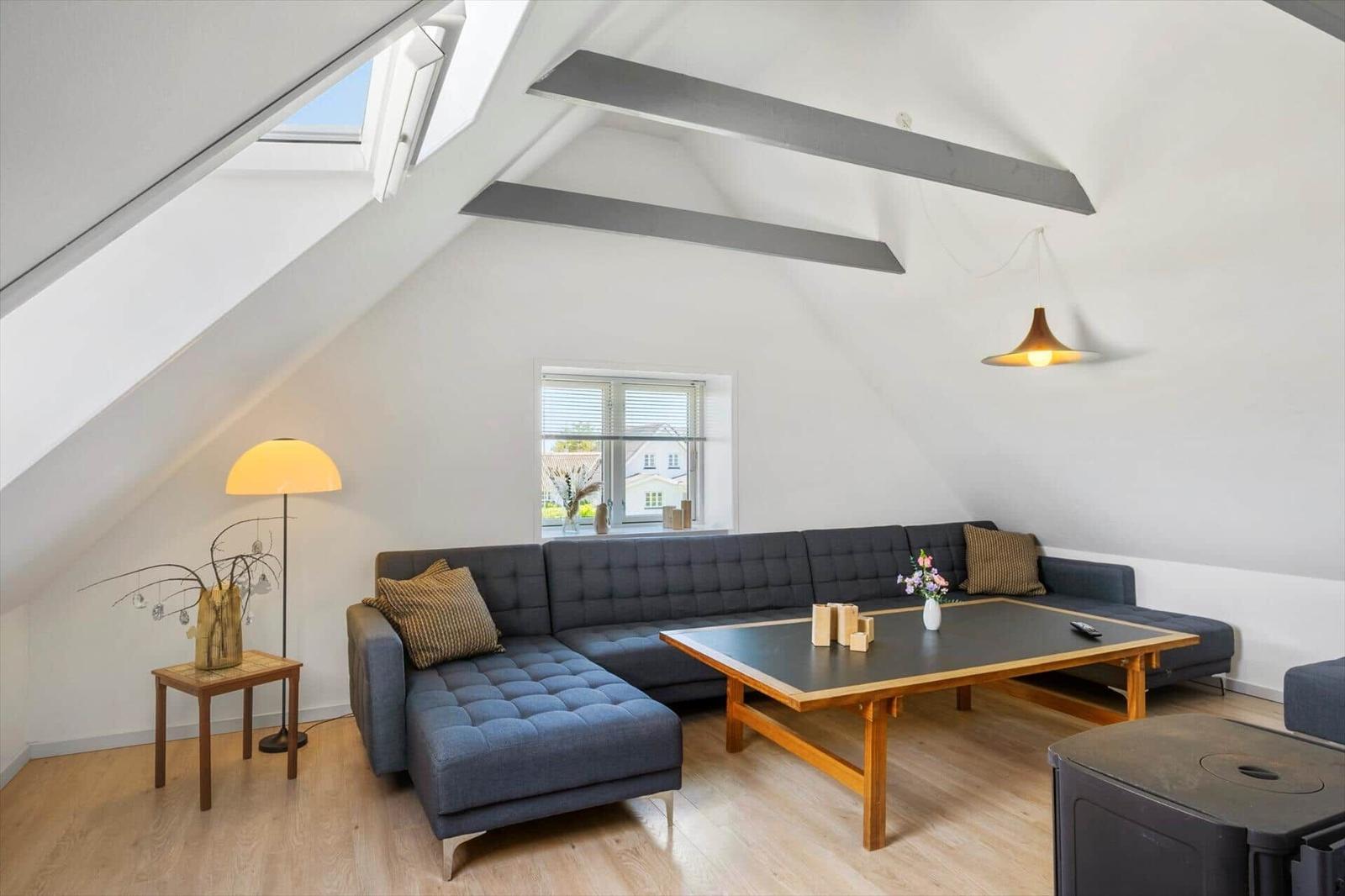 Wohnzimmer mit Dachschrägen, Sofa, Tisch und Fenster