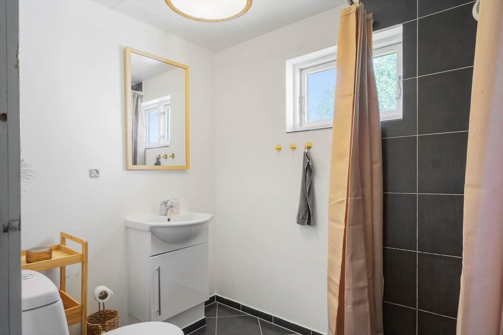 Badezimmer mit Waschbecken, Spiegel, Dusche und Fenster