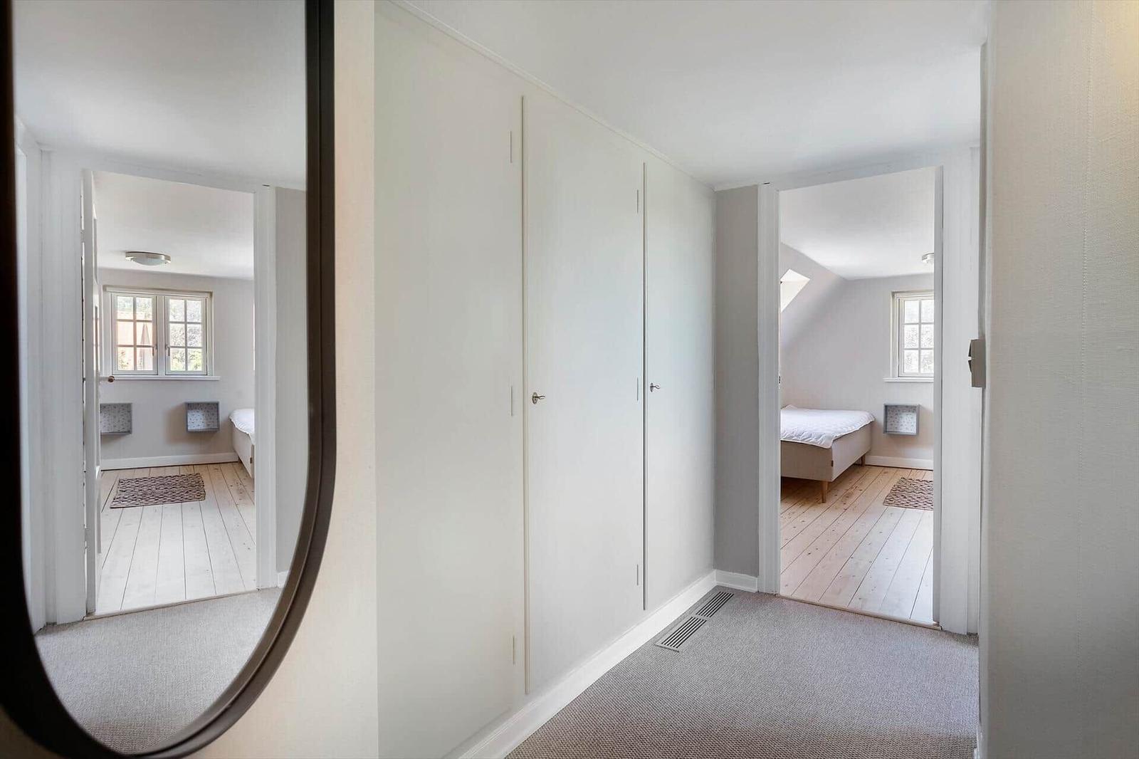 Flur mit Kleiderschrank und Blick in zwei Schlafzimmer mit Holzboden und Fenstern.