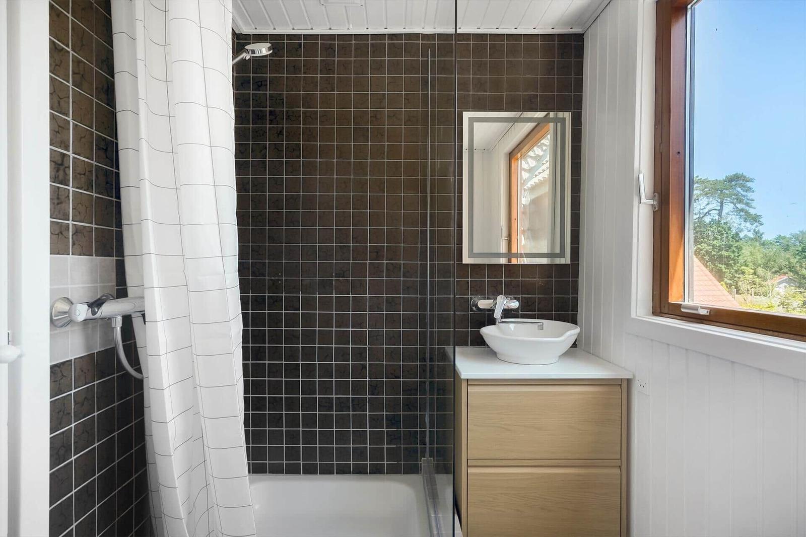 Bad mit Dusche, Waschbecken und Fenster mit Blick auf die Landschaft.