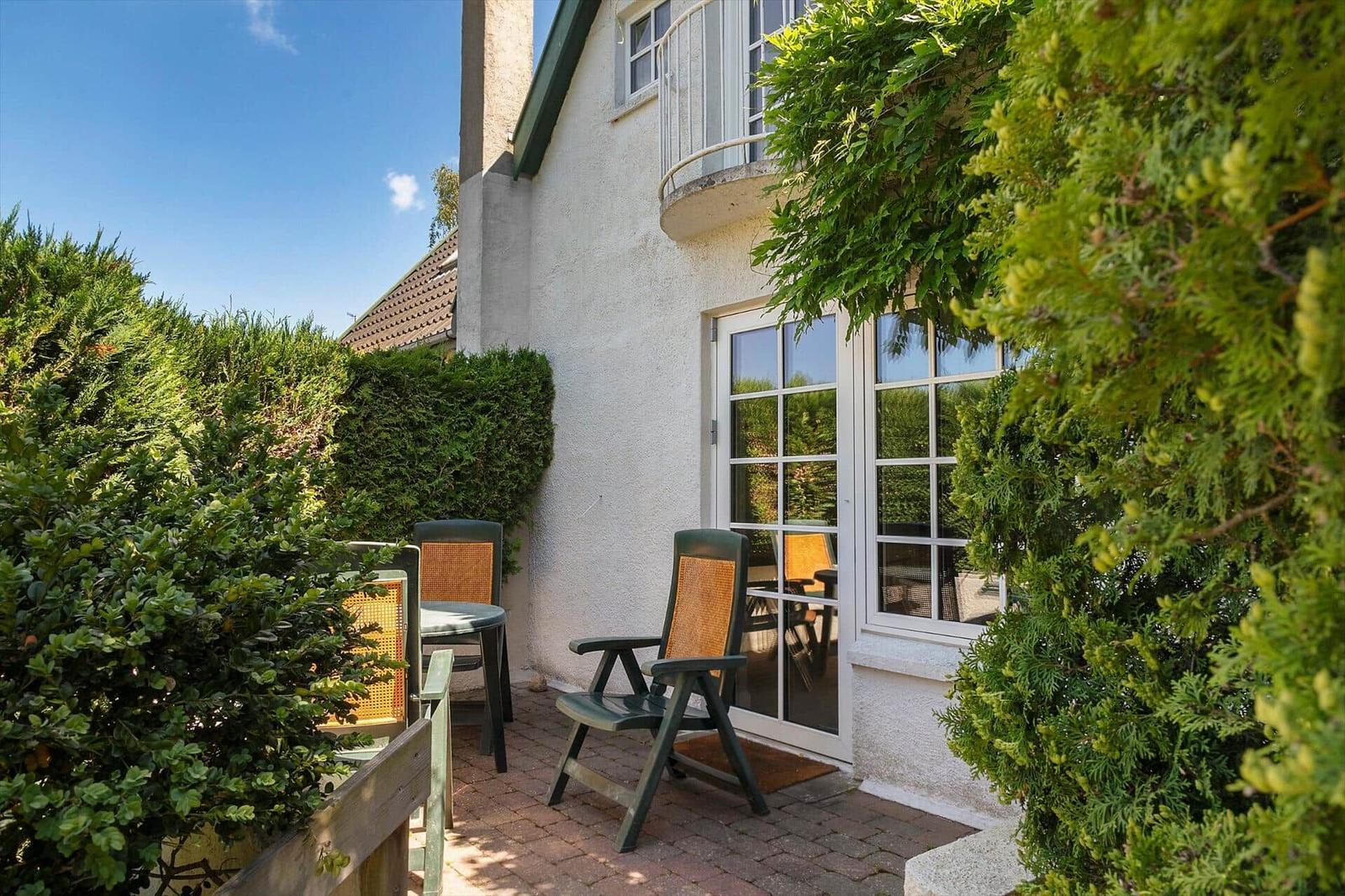 Terrasse mit Stuhl und Tisch vor einer Haustür mit Glasfenstern.