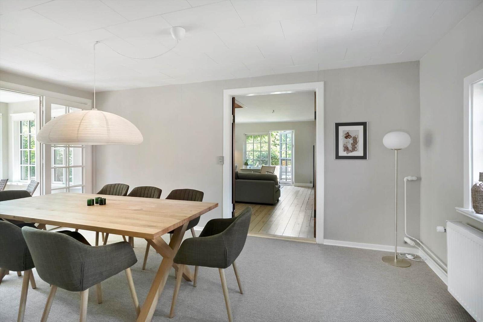 Esszimmer mit Holztisch und Stühlen, Blick in Wohnzimmer mit Sofa und Holzboden.