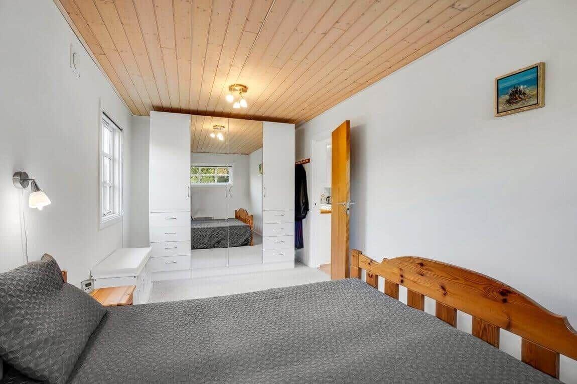 Schlafzimmer mit Holzboden, weißer Kleiderschrank und Holzbett.