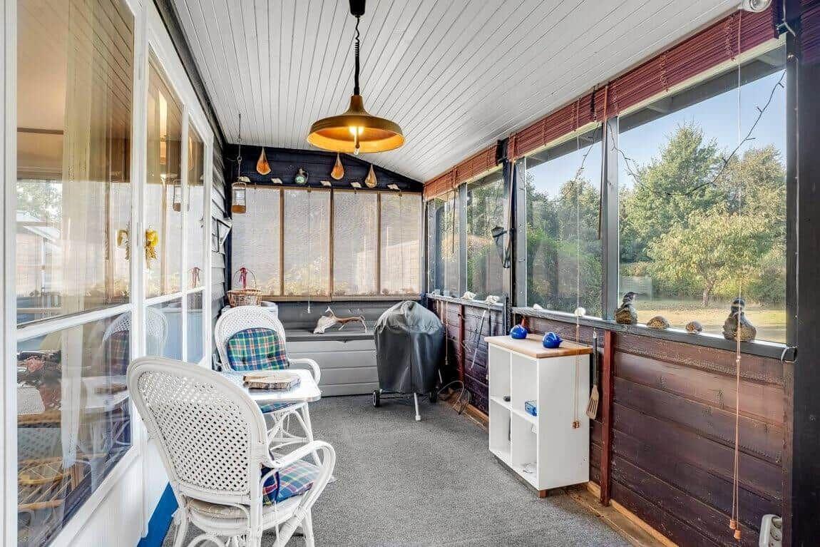 Gewölbter Raum mit weißen Stühlen, Fenstern und Deckenleuchte.