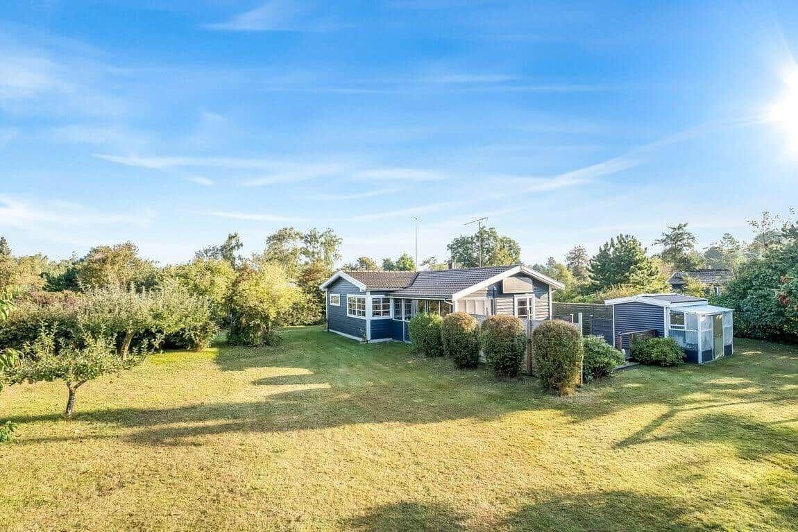 Ein blau-weißes Haus mit Garten und kleinem Nebengebäude unter blauem Himmel.