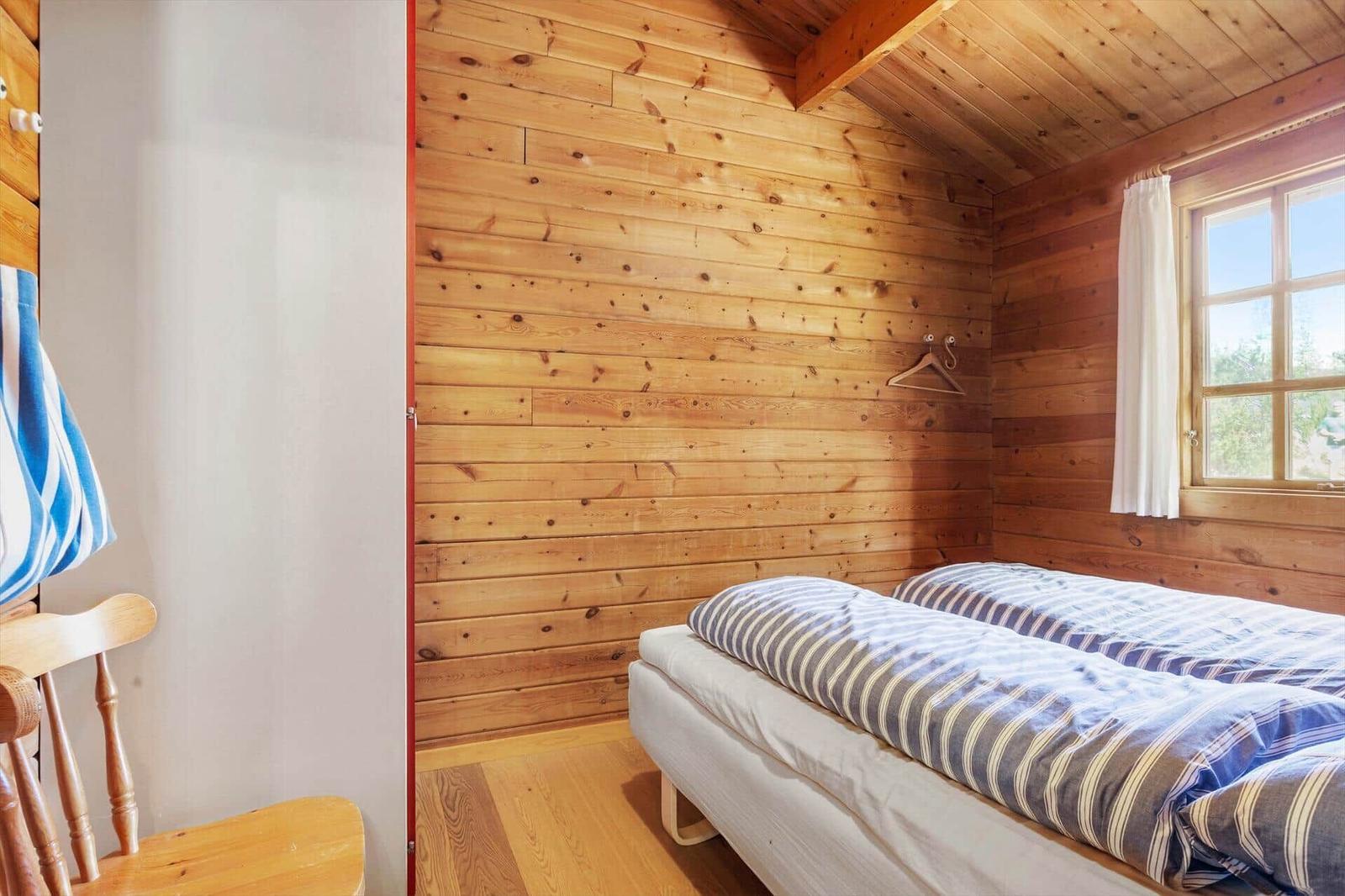 Schlafzimmer mit Holzwand, Bett und Fenster.