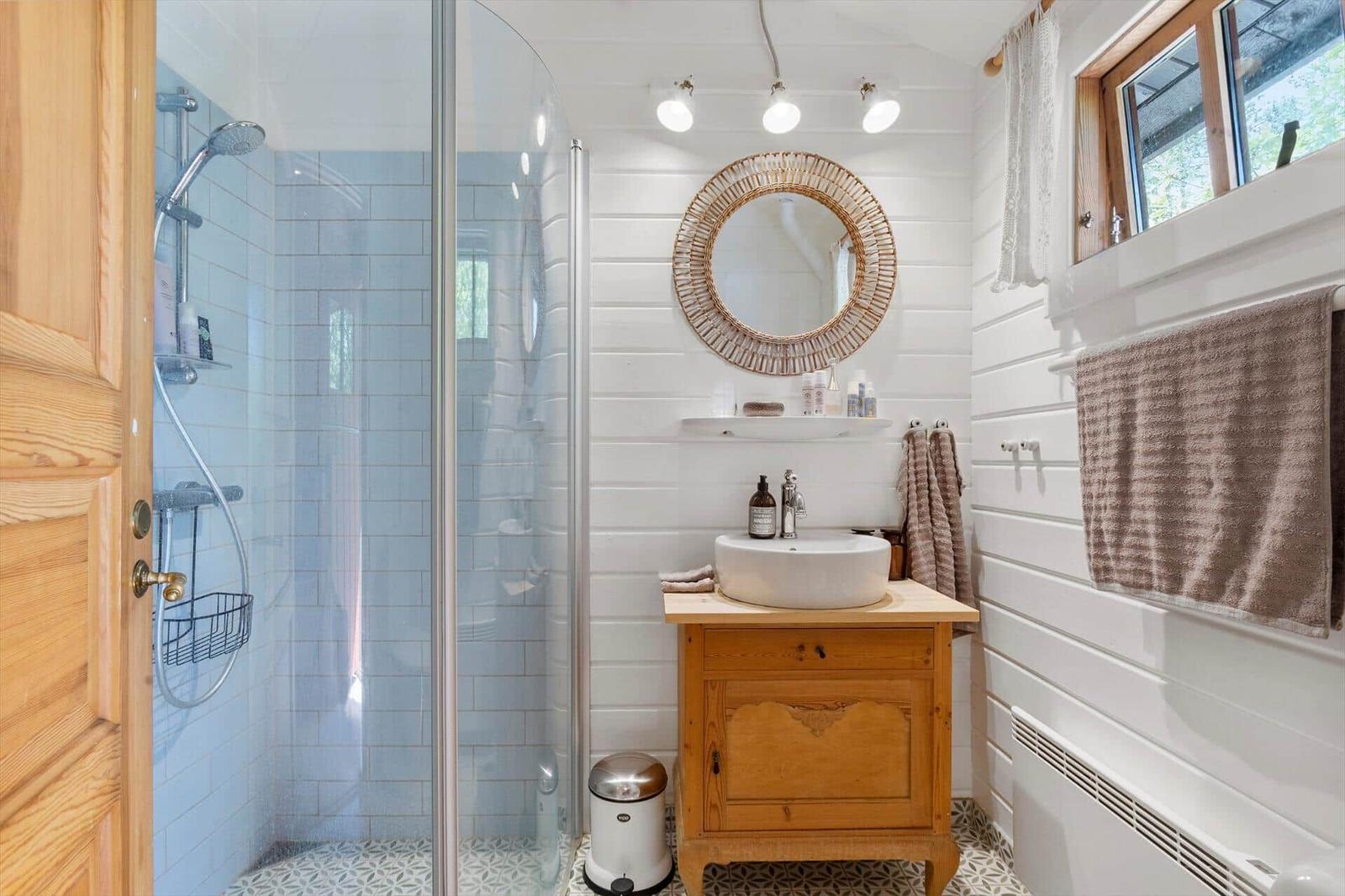 Badezimmer mit Dusche, Waschbecken und Spiegel