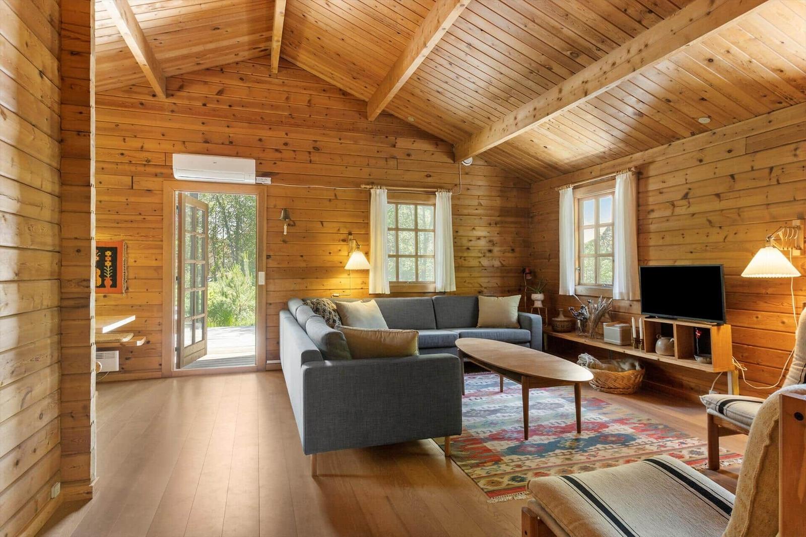 Wohnzimmer mit Holzwand, Sofa, Couchtisch und Fernseher