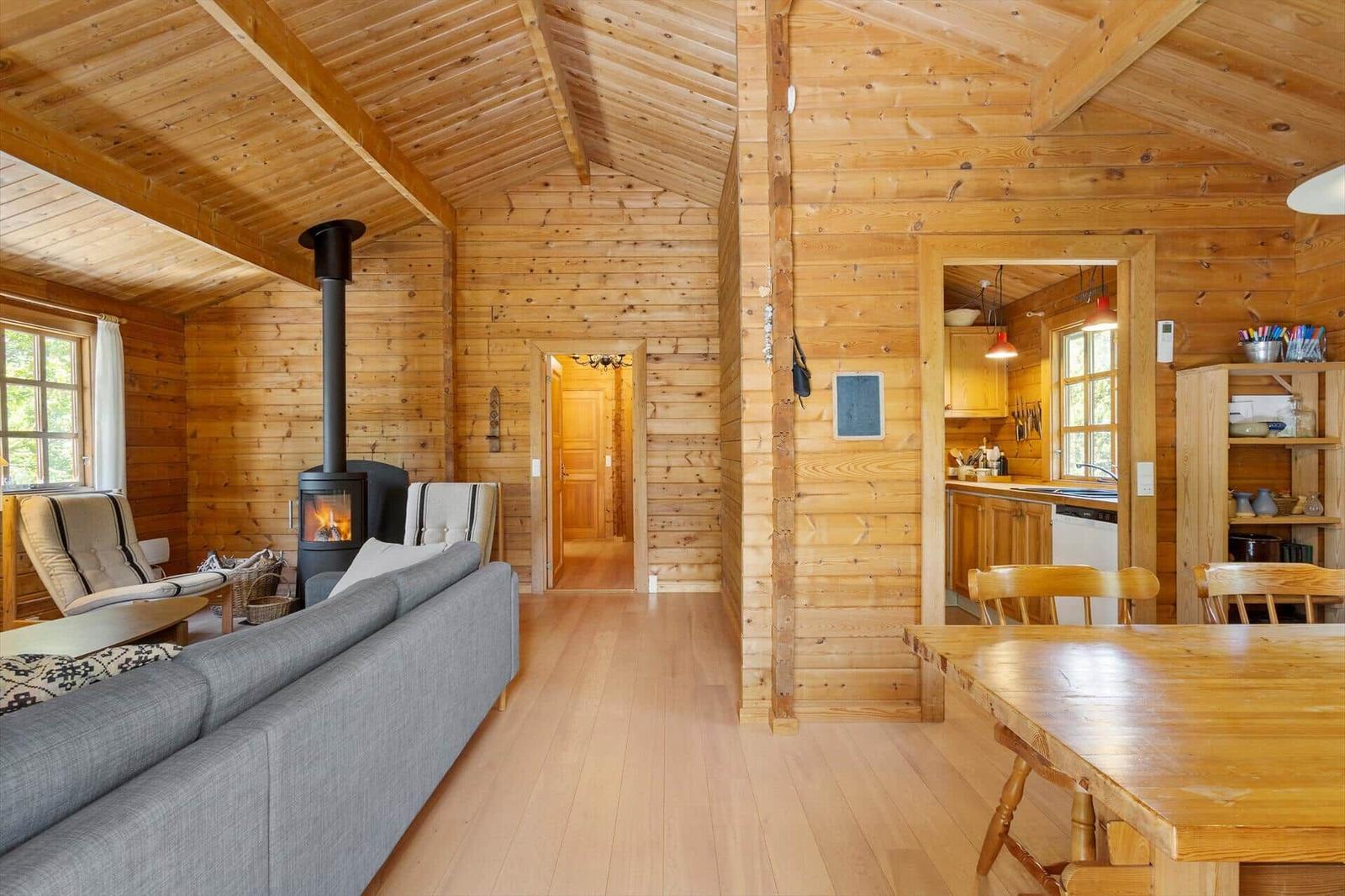 Wohn- und Essbereich mit Holzvertäfelung, Kamin und Küchenbereich.